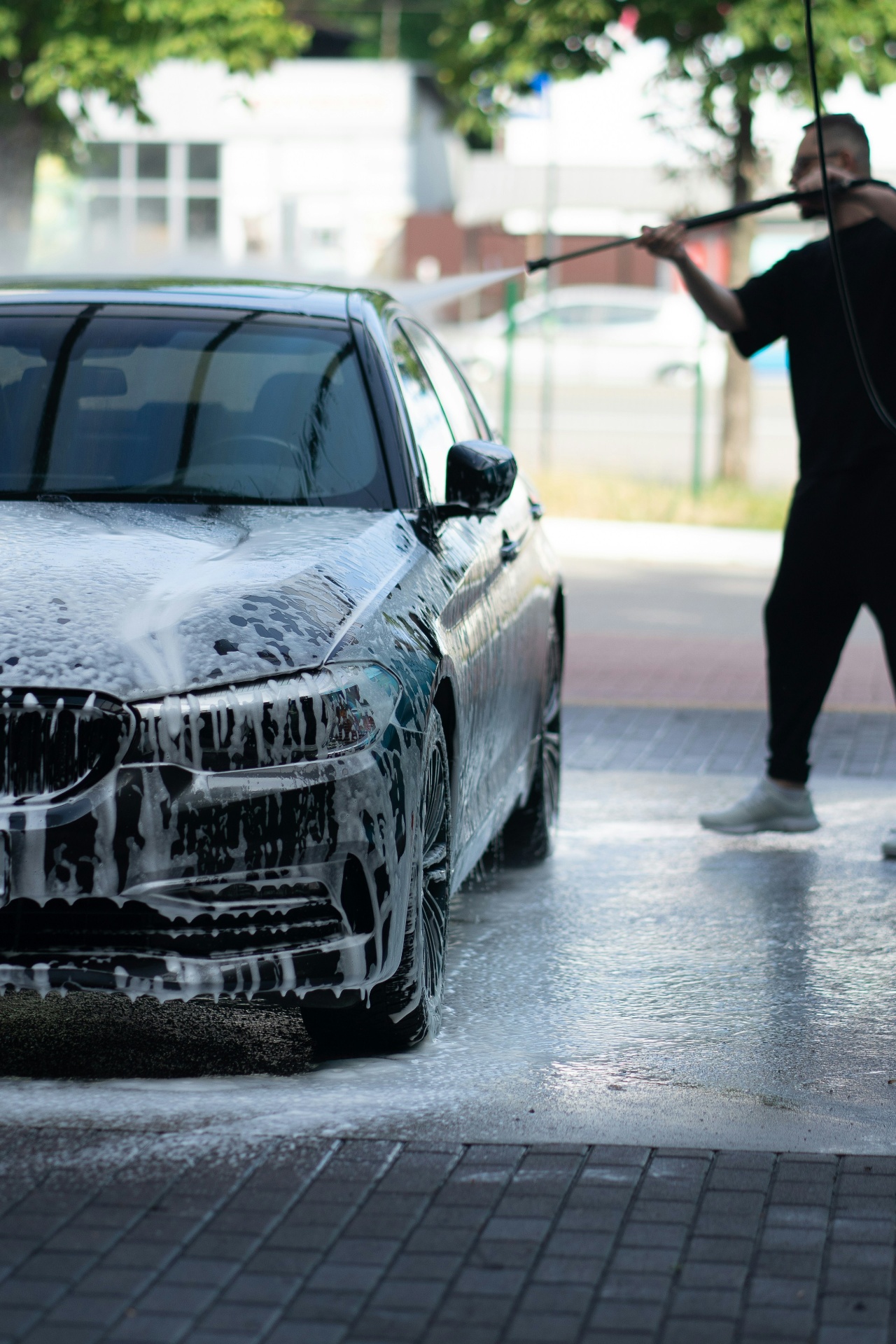 Mobile detailer pressure washing a luxury car