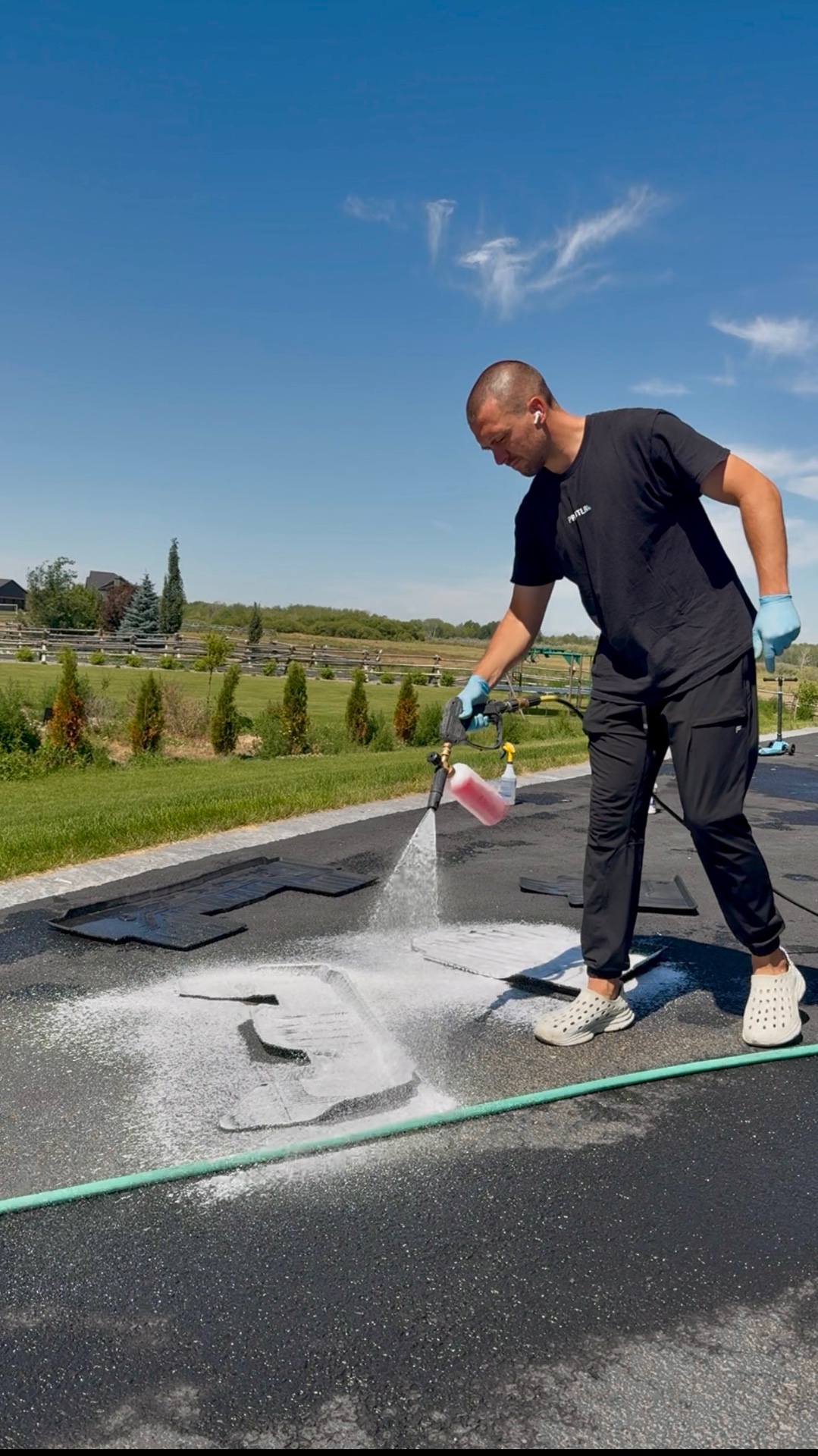 PRO DTLR detailer rinsing floor mats during a detail