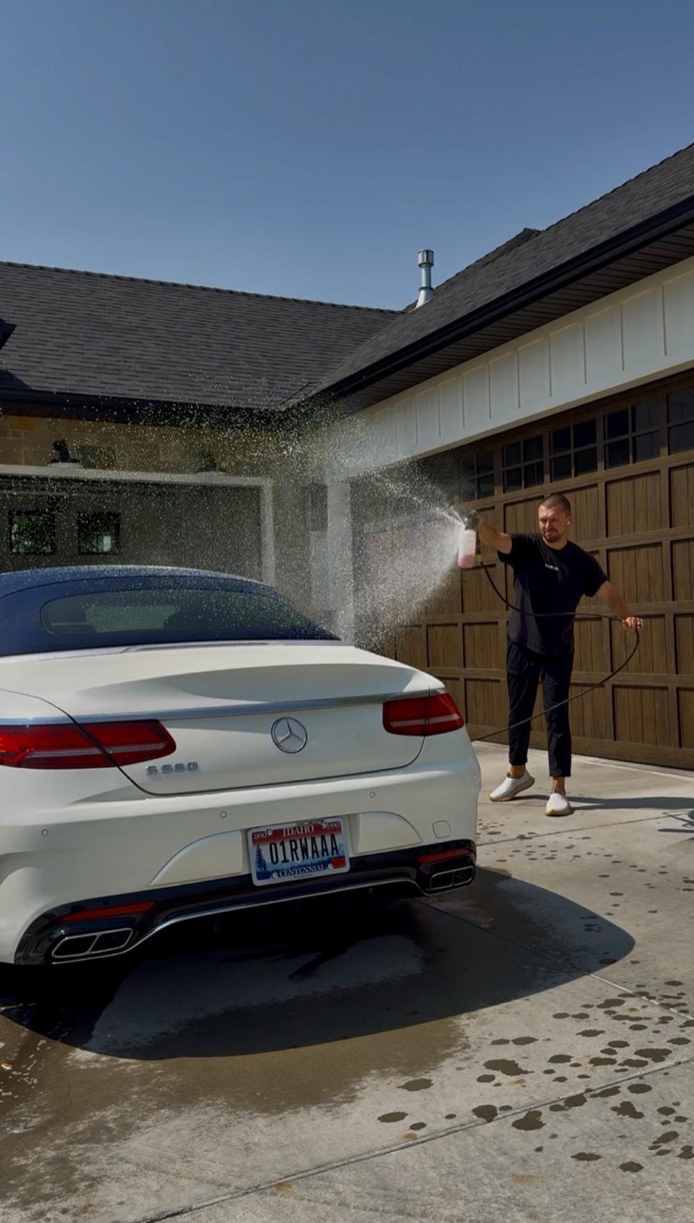 PRO DTLR detailer rinsing a customer's Mercedes convertible in their driveway
