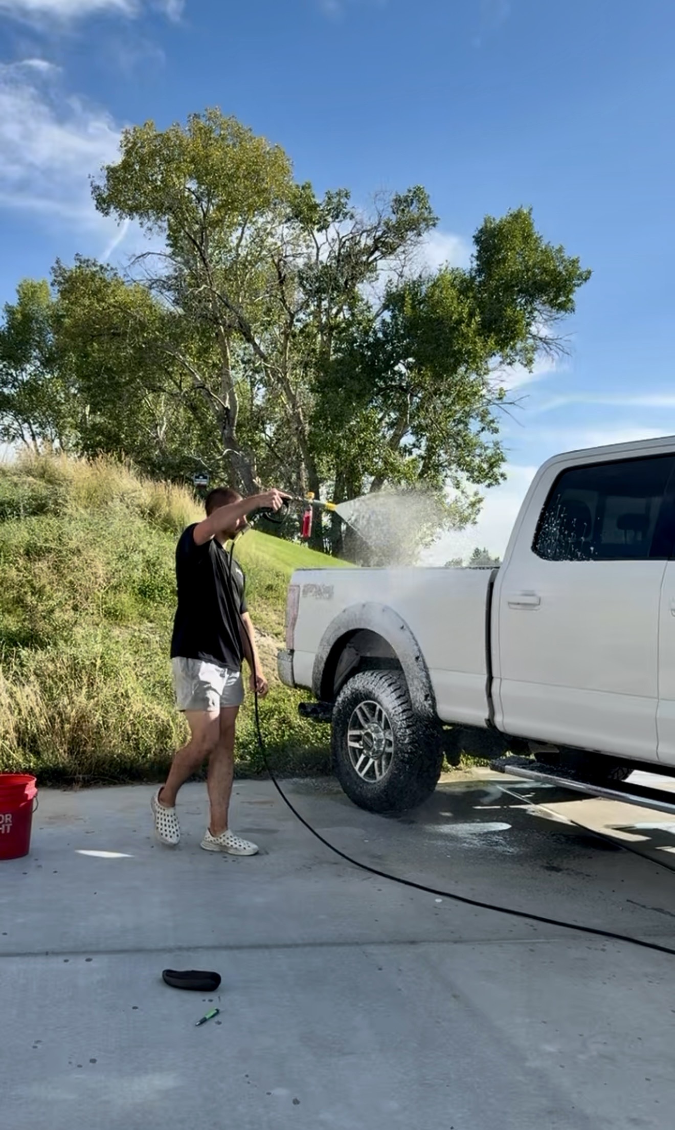 PRO DTLR detailer rinsing a truck bed with a pressure washer during a PRO Reset service
